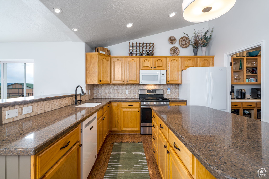 Kitchen with white appliances, a sink, vaulted ceiling, backsplash, and a textured ceiling