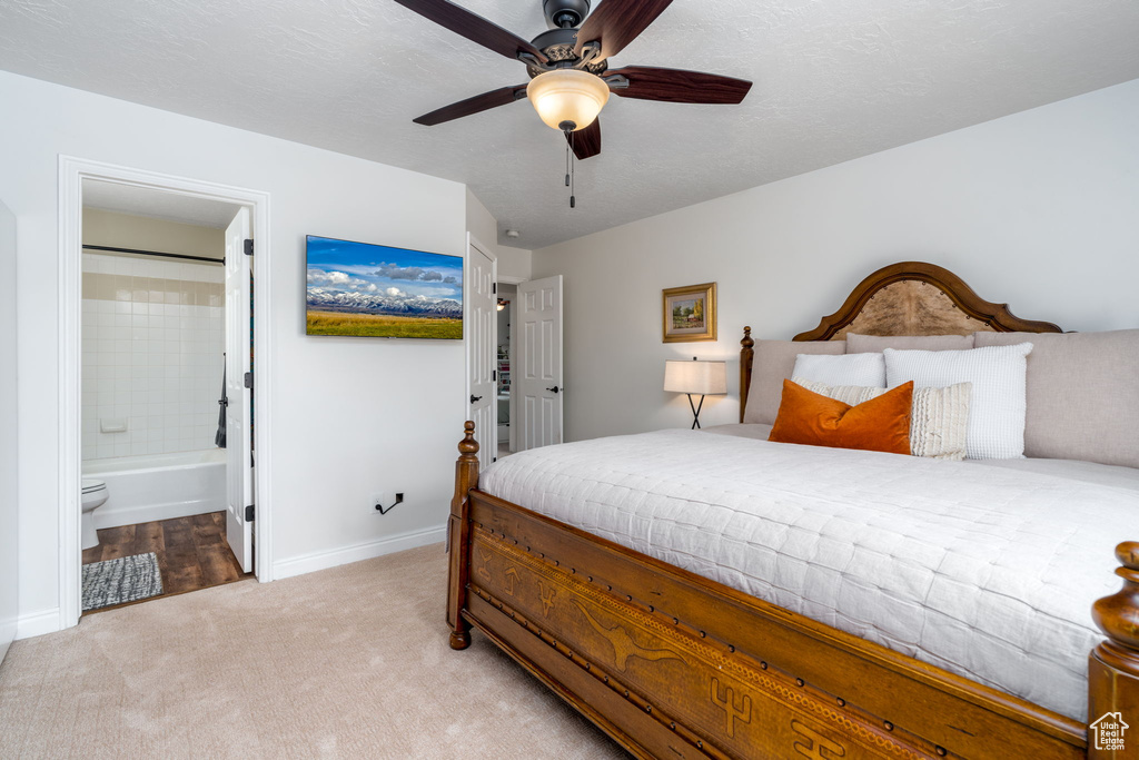 Bedroom featuring light colored carpet, baseboards, connected bathroom, and a ceiling fan