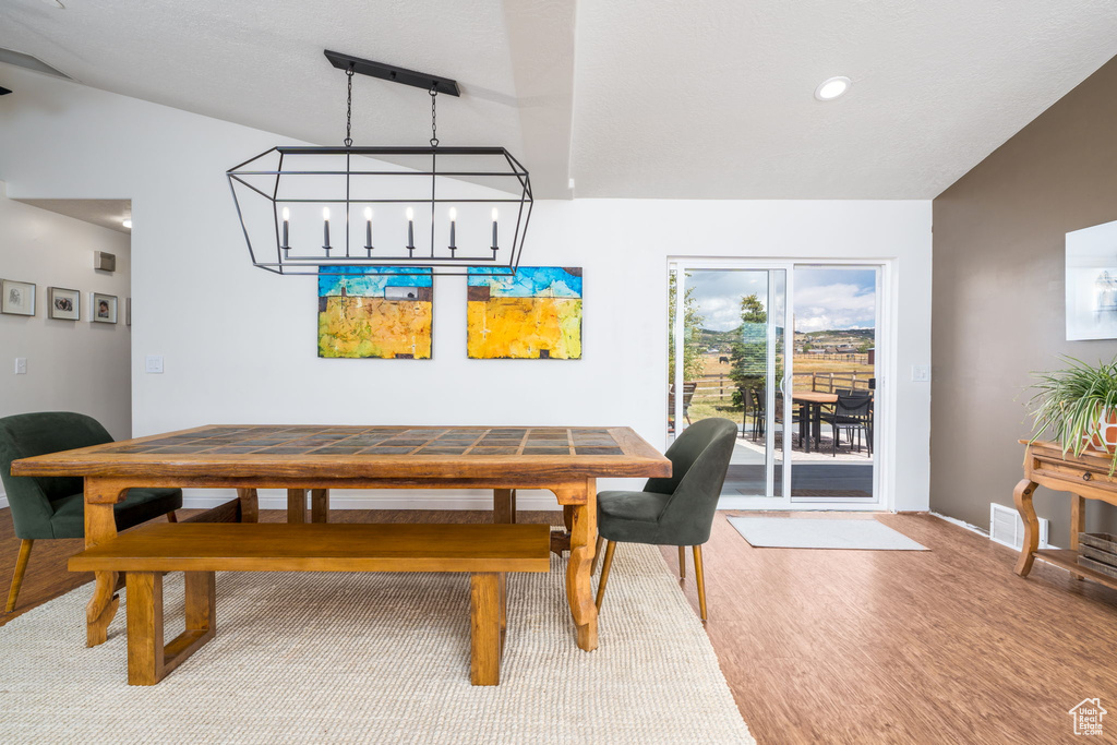 Dining room featuring wood finished floors, baseboards, vaulted ceiling, and recessed lighting