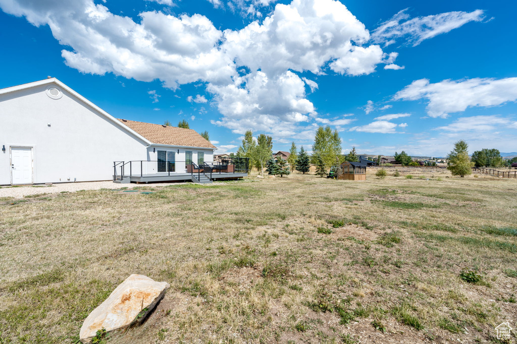 View of grassy yard with a wooden deck