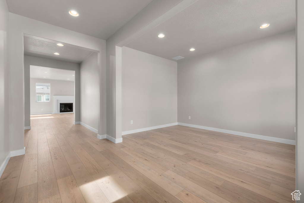 Spare room with light wood-type flooring, baseboards, a fireplace, and recessed lighting