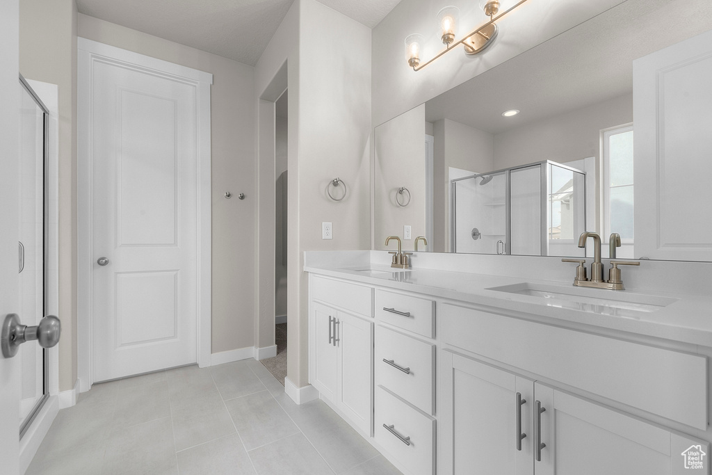 Full bath with a stall shower, double vanity, tile patterned flooring, and baseboards