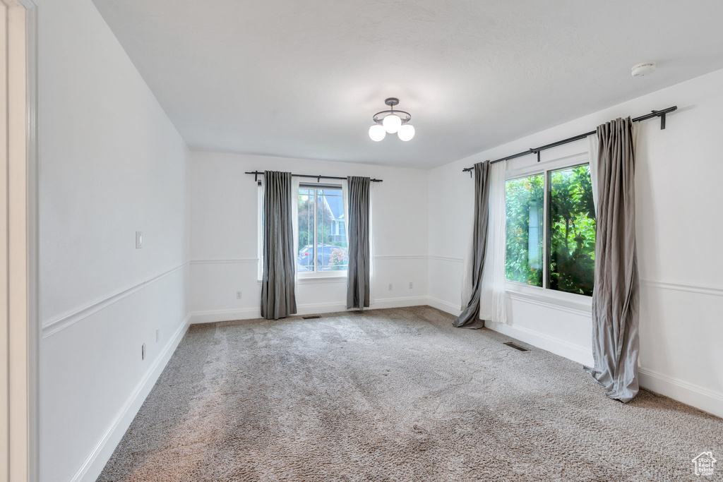 Carpeted spare room with plenty of natural light, a smoke detector, and baseboards