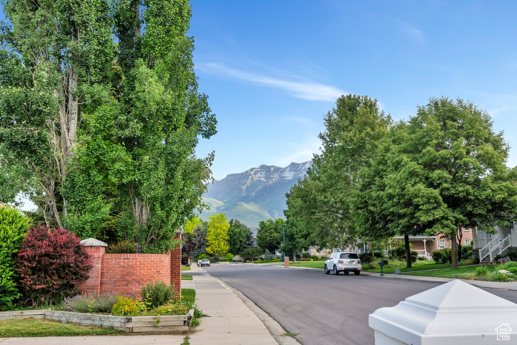 View of asphalt street featuring curbs, a mountain view, and sidewalks