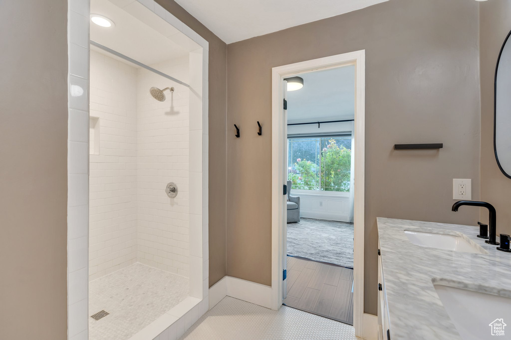 Full bath with a tile shower, double vanity, and tile patterned floors