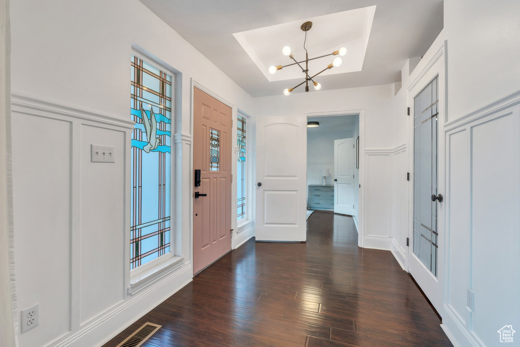 Entryway featuring a decorative wall, a chandelier, dark wood-type flooring, plenty of natural light, and a wainscoted wall