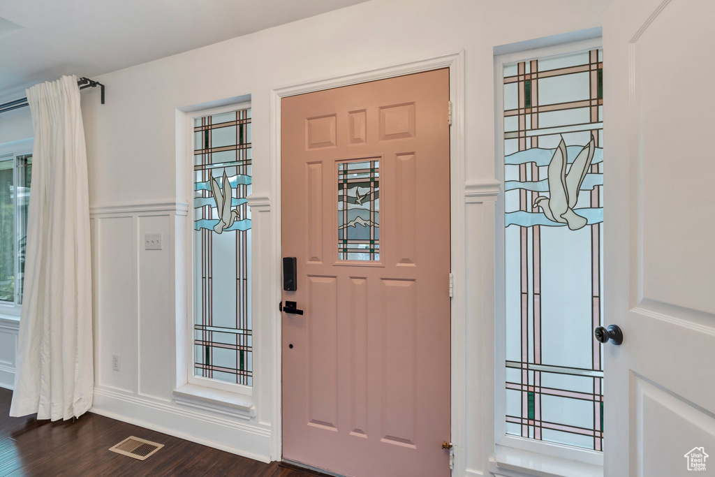 Entryway with dark wood-type flooring, a decorative wall, and a wainscoted wall