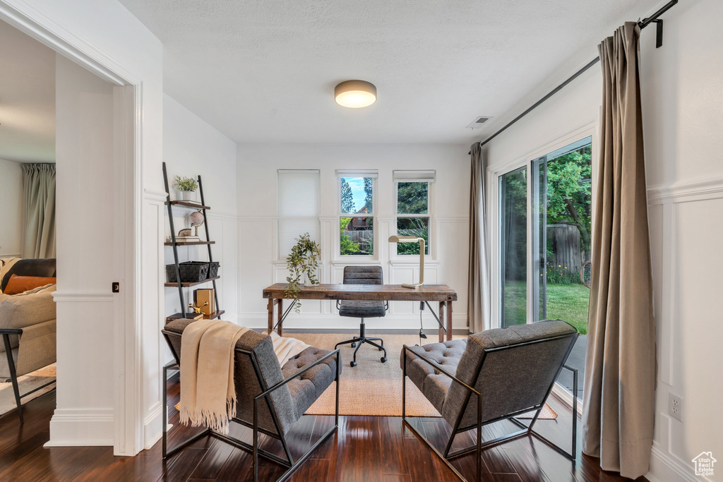 Office space with a decorative wall, dark wood-style floors, and a wainscoted wall