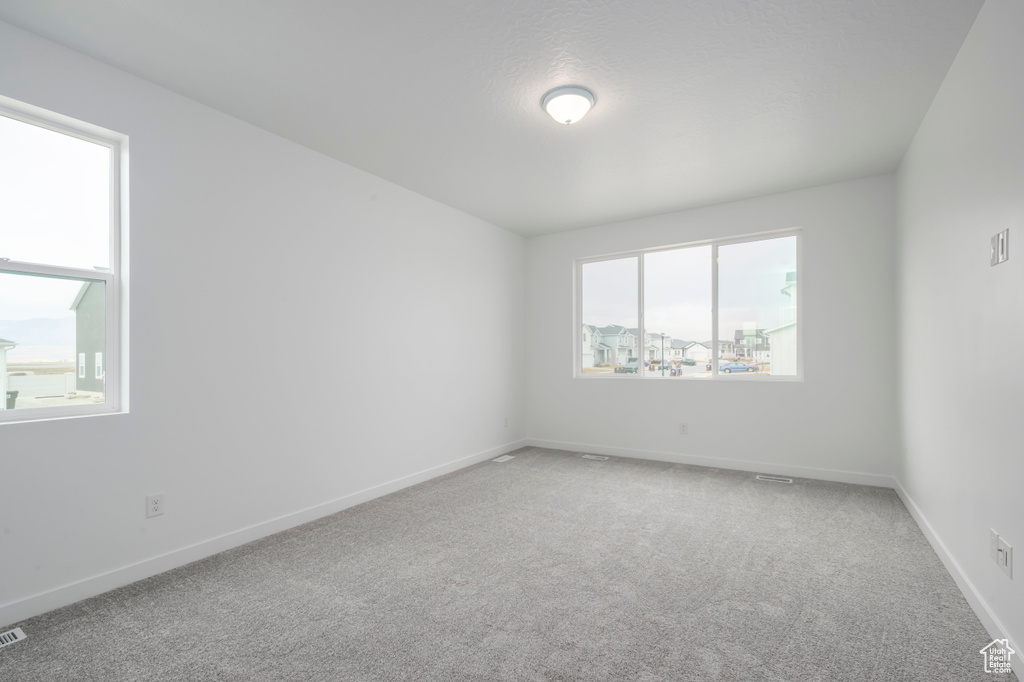 Unfurnished room featuring light carpet and baseboards