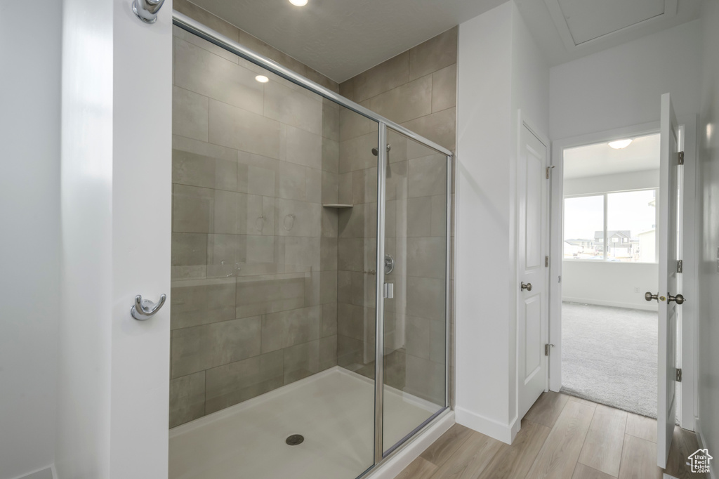 Full bath with wood finished floors, a shower stall, baseboards, and recessed lighting