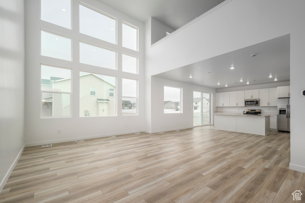 Unfurnished living room with light wood-style flooring, baseboards, and recessed lighting