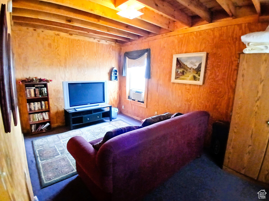 Living room featuring beamed ceiling, wood walls, and cooling unit