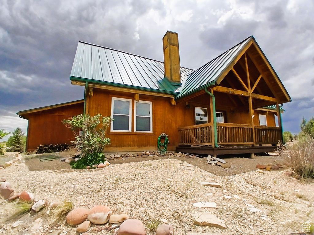 Back of property featuring a chimney, a standing seam roof, metal roof, and a wooden deck