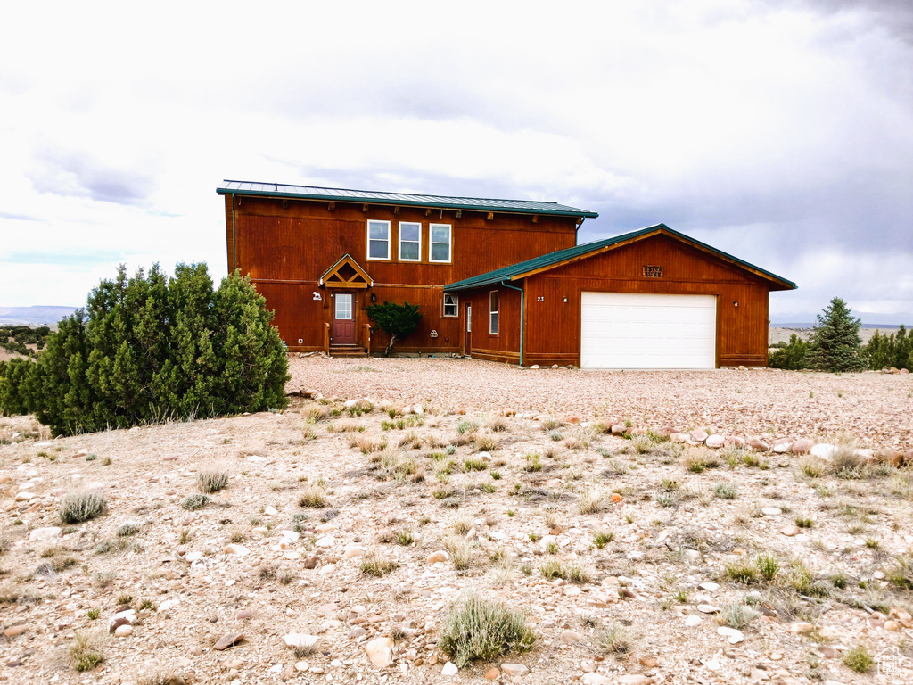 Chalet / cabin featuring a garage and gravel driveway