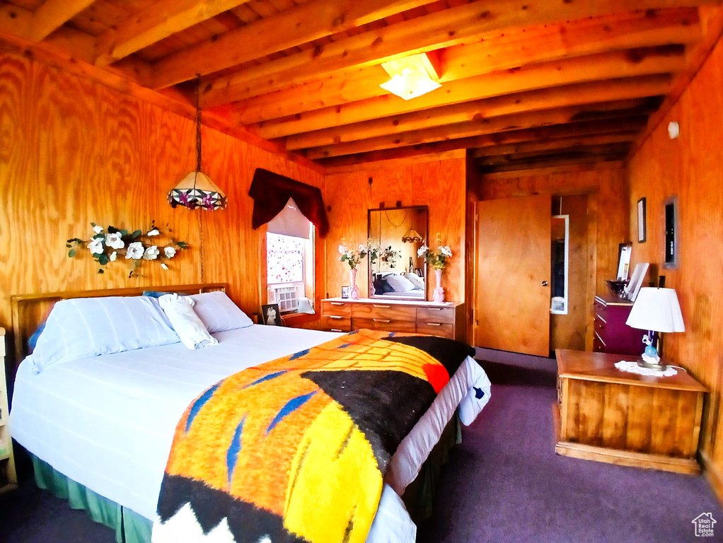 Bedroom featuring beam ceiling, wood walls, and carpet flooring