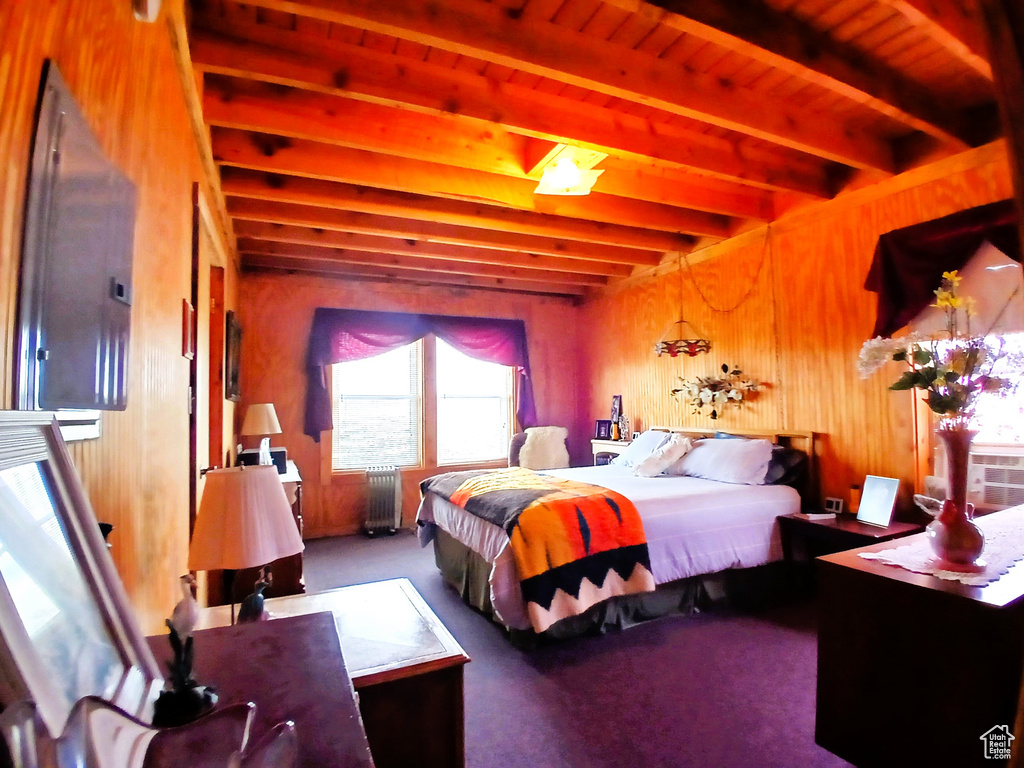 Bedroom with beam ceiling, carpet floors, and wood walls