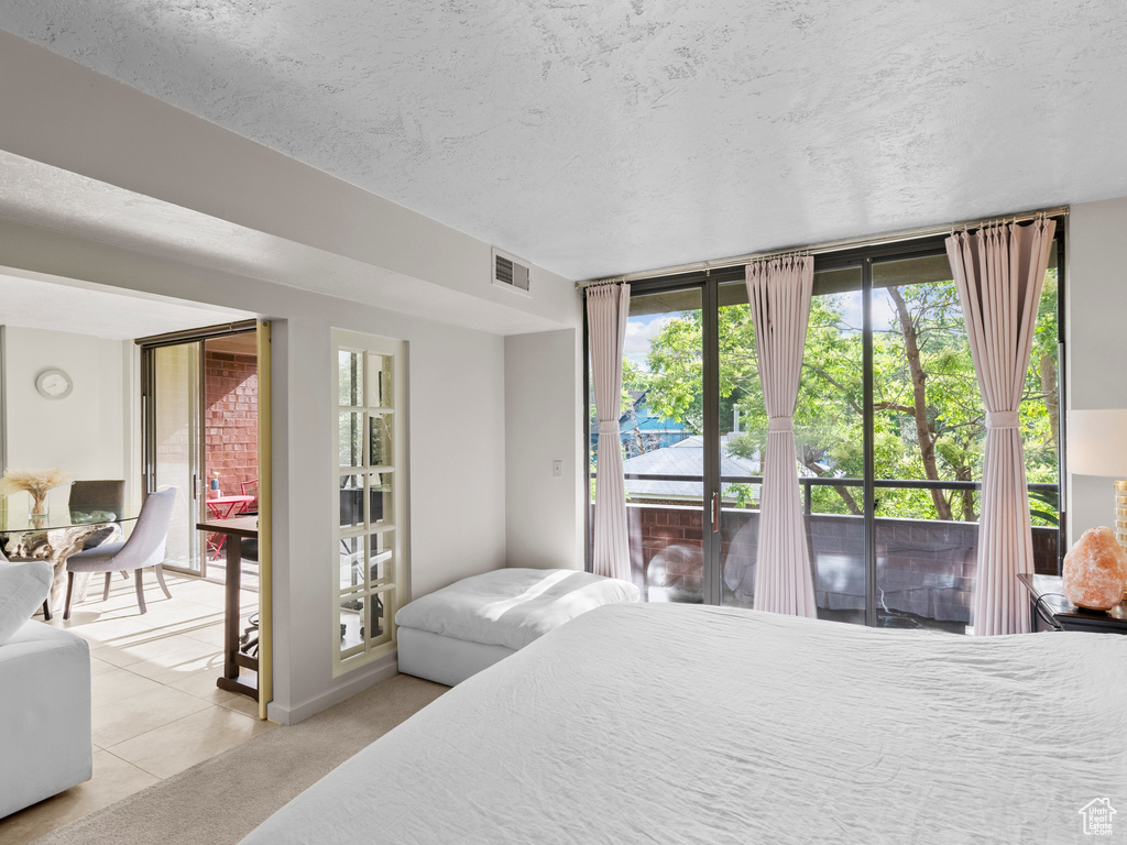 Bedroom with access to exterior, light tile patterned floors, and a textured ceiling