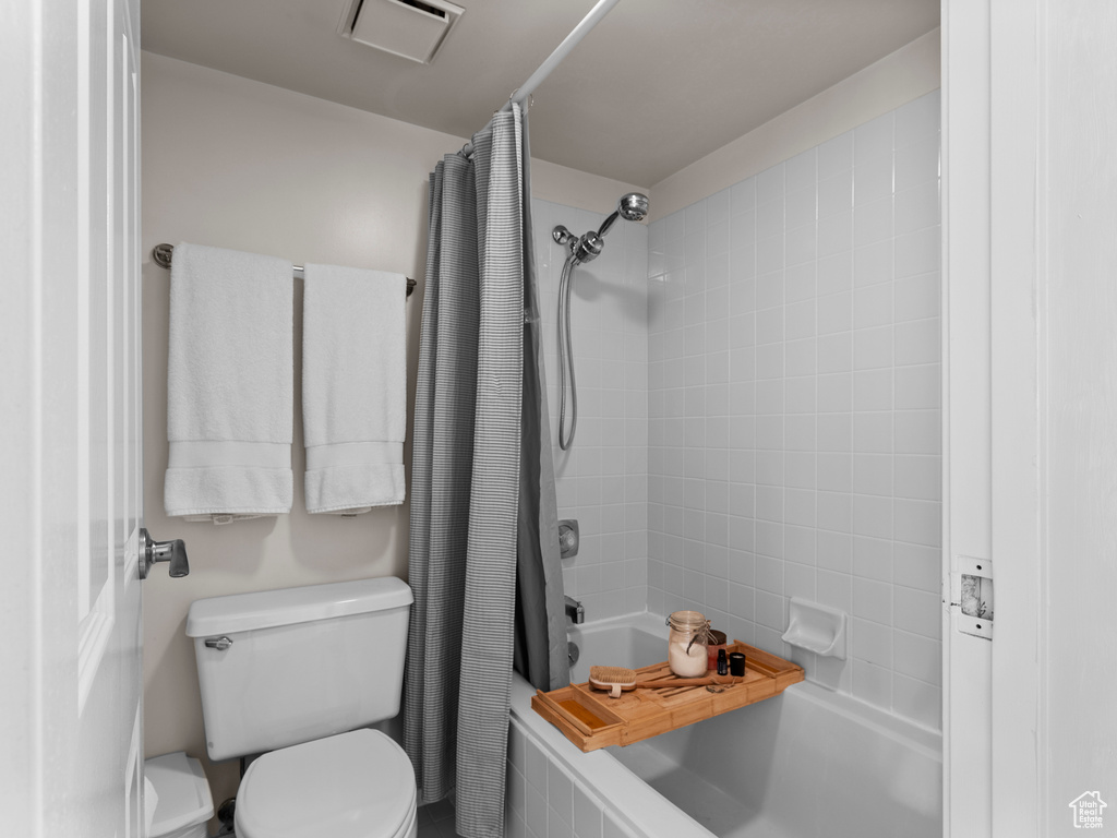 Bathroom featuring shower / bath combination with curtain and toilet