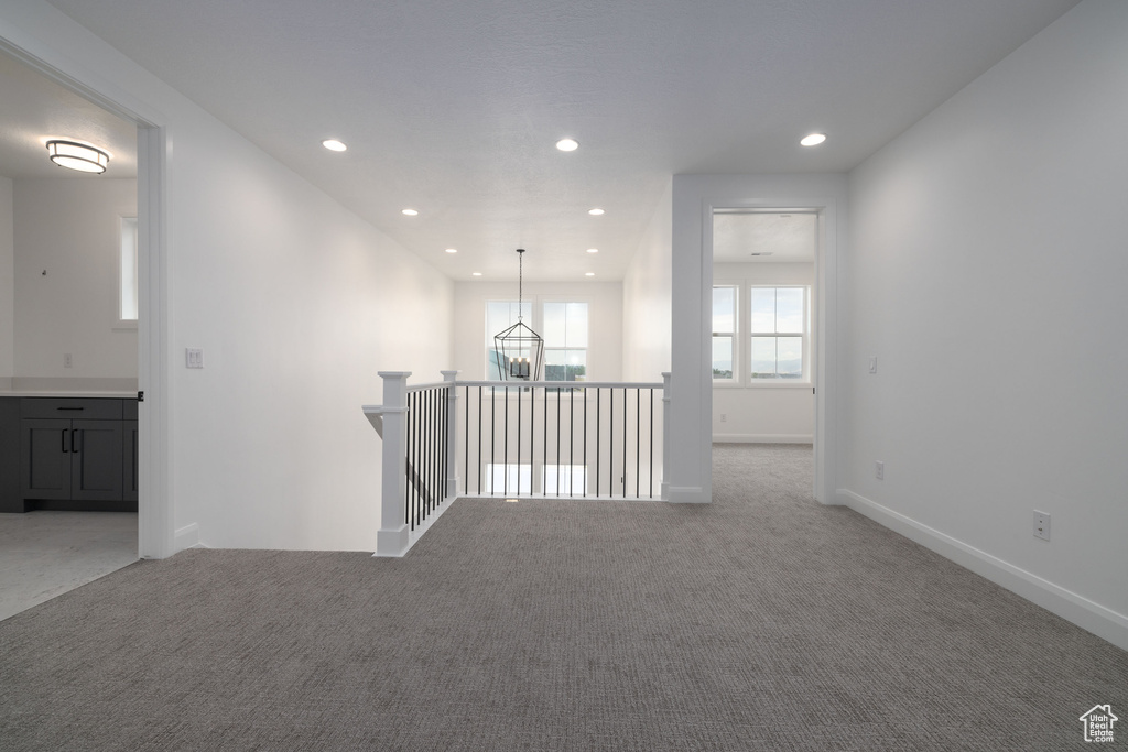 Unfurnished room featuring light carpet, recessed lighting, baseboards, and a chandelier