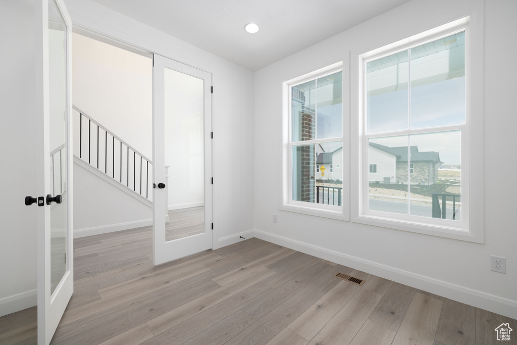 Empty room featuring baseboards, plenty of natural light, light wood-style flooring, french doors, and recessed lighting