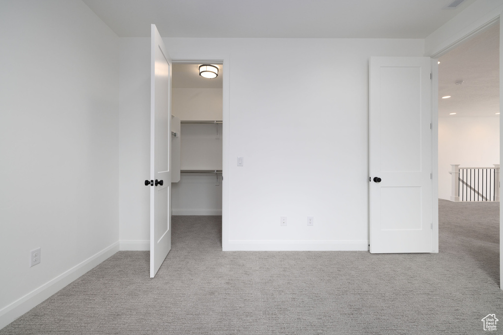 Unfurnished bedroom with carpet, baseboards, recessed lighting, and a walk in closet