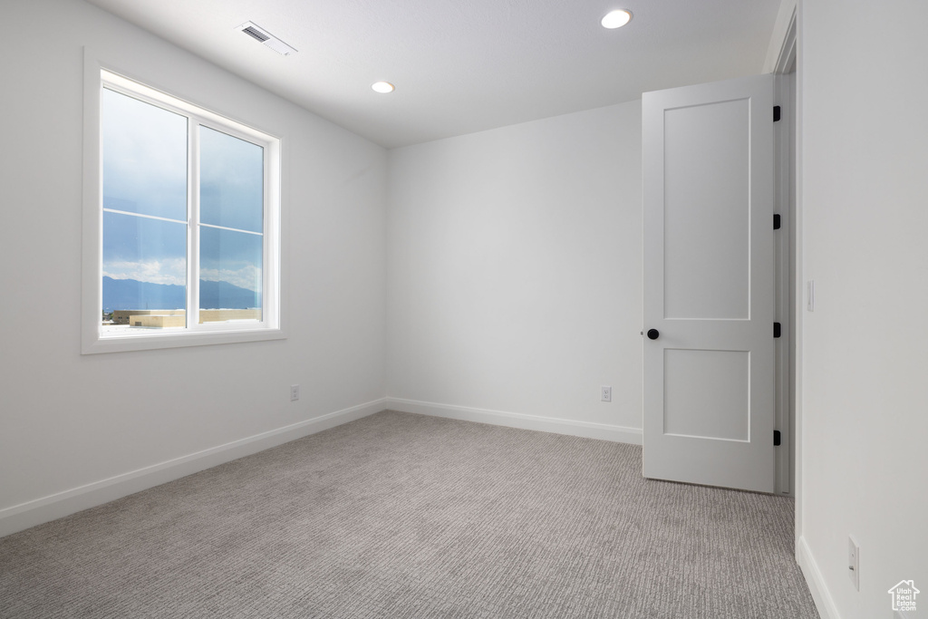 Empty room featuring light carpet, recessed lighting, and baseboards