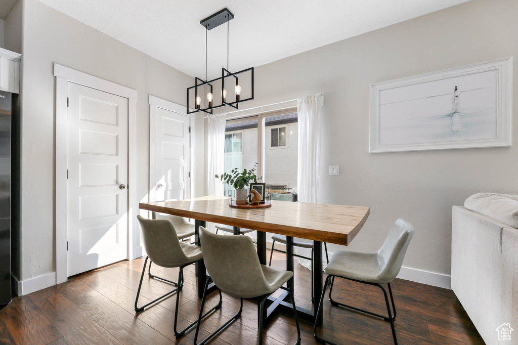 Dining room featuring a chandelier, baseboards, and dark wood-type flooring