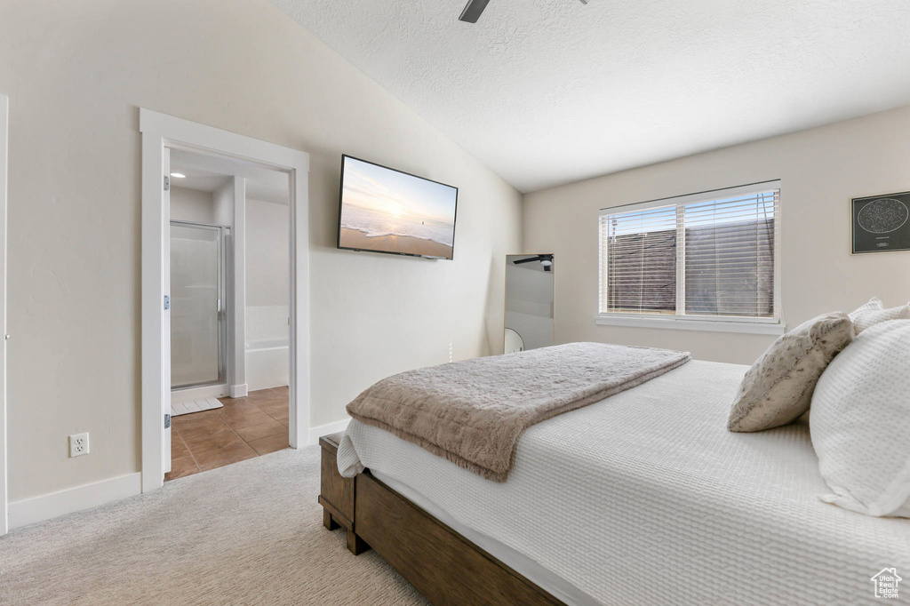 Carpeted bedroom featuring vaulted ceiling, baseboards, a ceiling fan, tile patterned floors, and connected bathroom