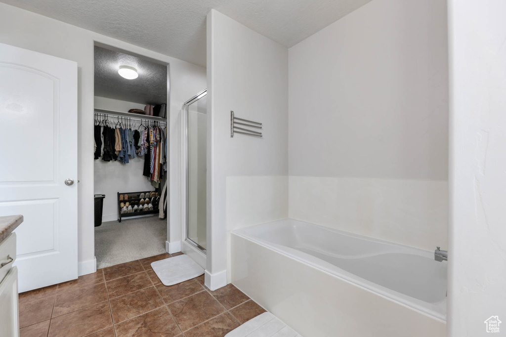 Bathroom with a garden tub, a shower stall, vanity, a spacious closet, and a textured ceiling