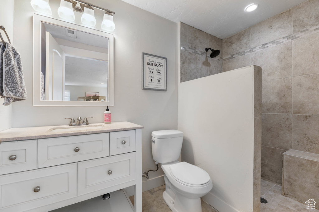 Full bath with vanity, walk in shower, toilet, and baseboards