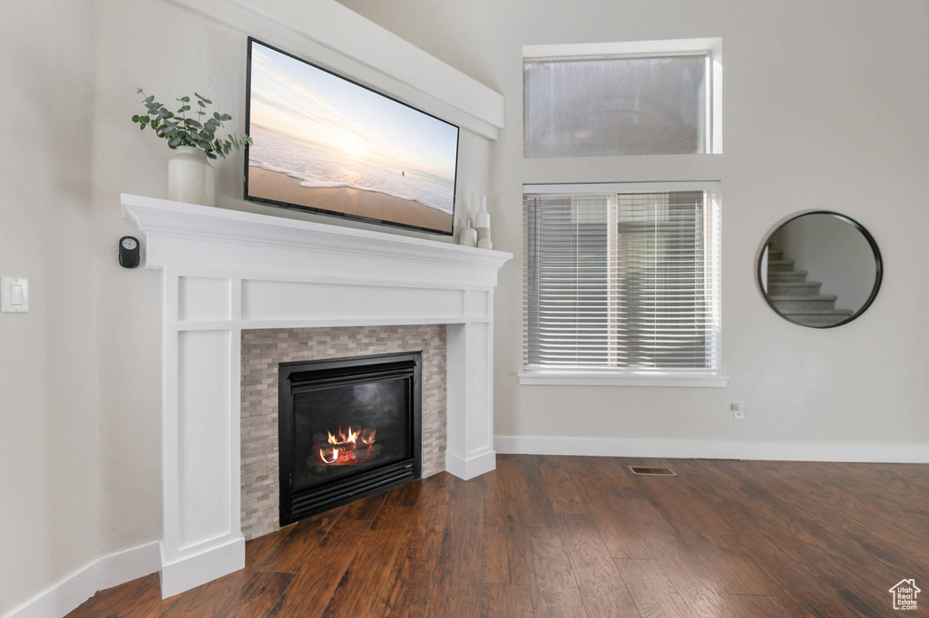Unfurnished living room with a tiled fireplace, wood finished floors, and baseboards