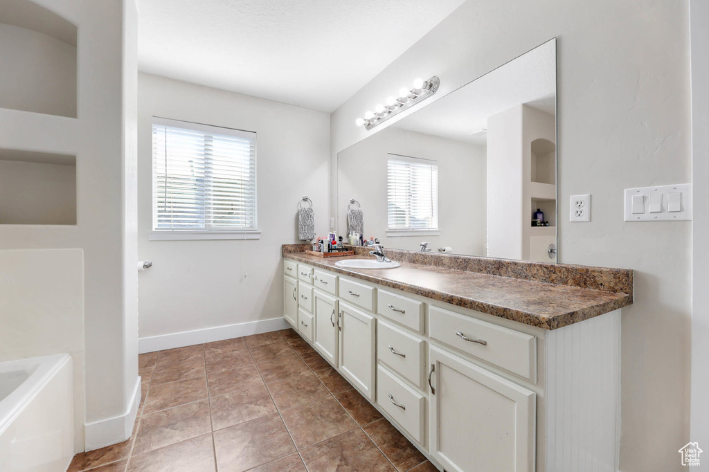 Bathroom with vanity, a garden tub, baseboards, and tile patterned floors