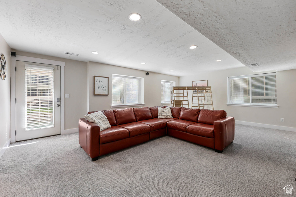 Living area with a textured ceiling, baseboards, light colored carpet, healthy amount of natural light, and recessed lighting