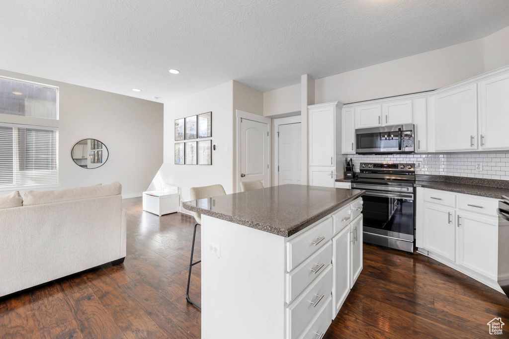 Kitchen featuring stainless steel appliances, open floor plan, a breakfast bar, backsplash, and recessed lighting