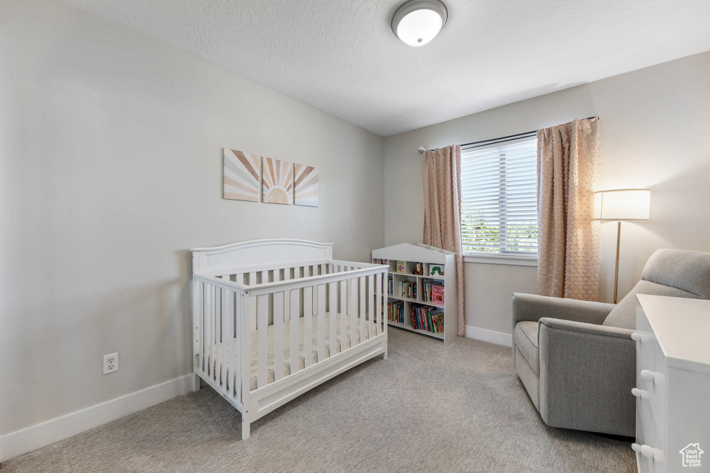 Bedroom featuring carpet floors, baseboards, and a crib
