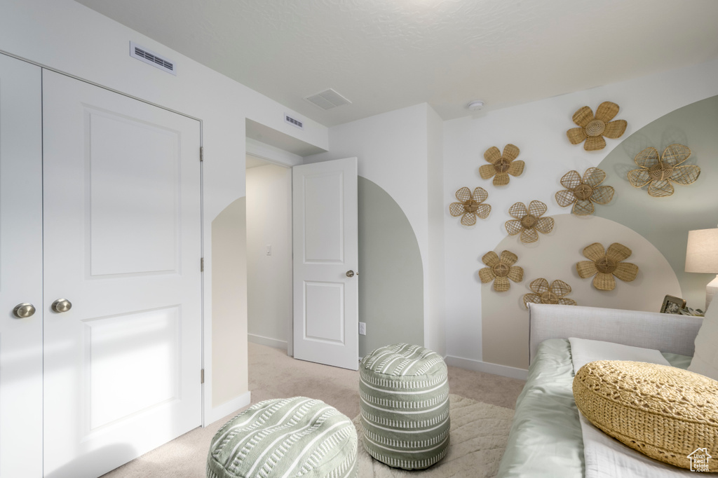 Sitting room featuring arched walkways, light colored carpet, and baseboards