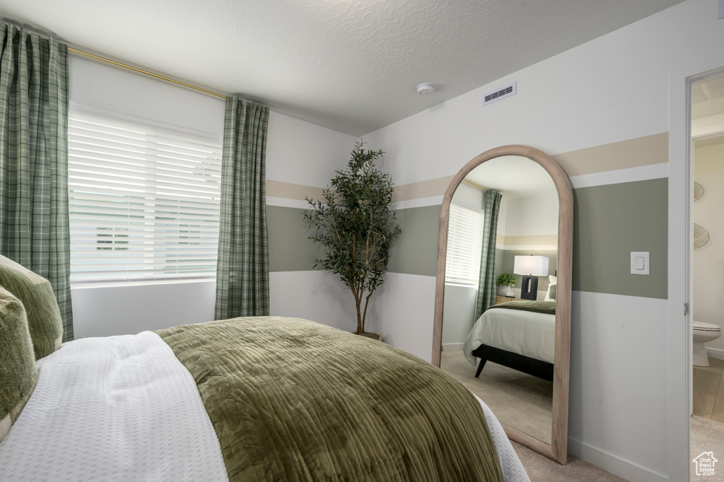 Bedroom with light carpet and multiple windows