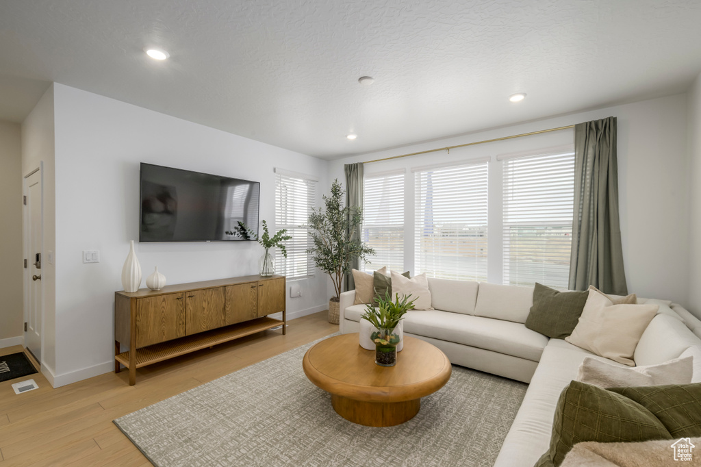 Living area with light wood finished floors, baseboards, and recessed lighting