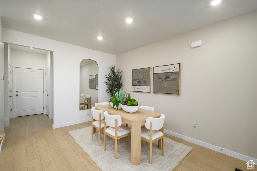 Dining area with arched walkways, light wood finished floors, recessed lighting, and baseboards