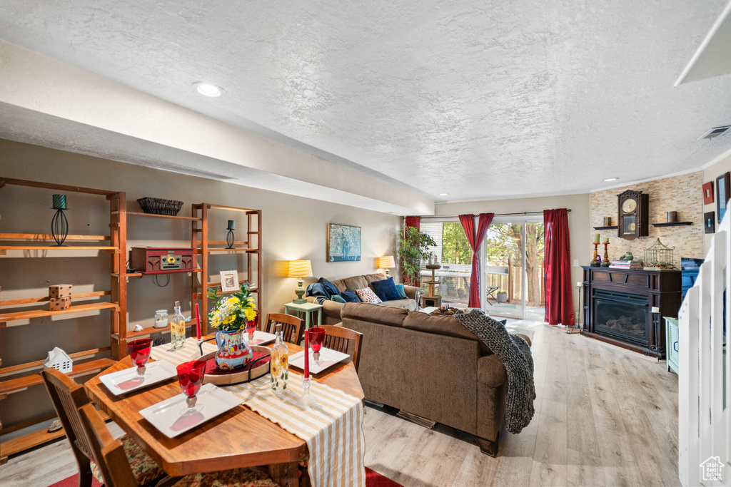 Living room featuring wood finished floors, a textured ceiling, a glass covered fireplace, and recessed lighting