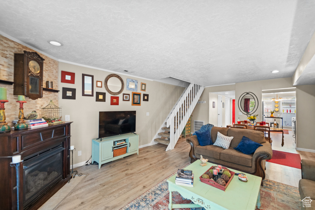 Living area featuring stairway, light wood-type flooring, a glass covered fireplace, baseboards, and recessed lighting