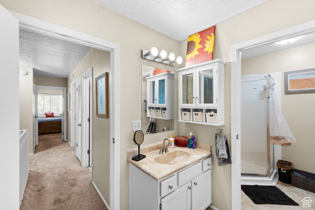 Bathroom with a textured ceiling, a shower stall, and vanity