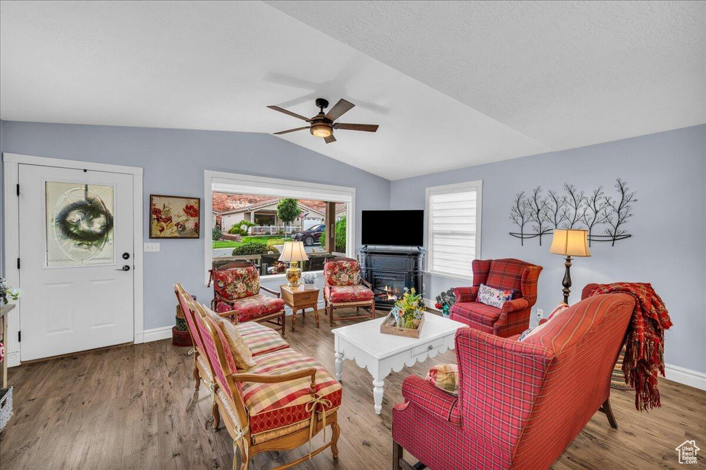 Living room featuring lofted ceiling, ceiling fan, baseboards, and wood finished floors
