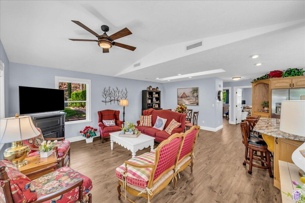 Living area with vaulted ceiling, baseboards, ceiling fan, light wood-type flooring, and recessed lighting