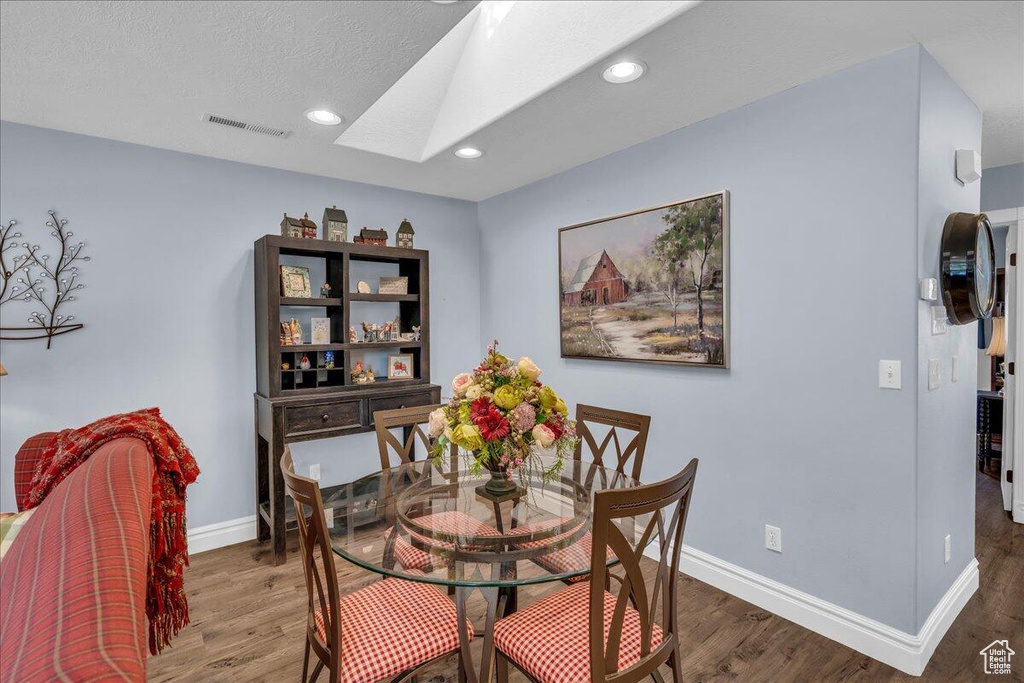 Dining space with a skylight, wood finished floors, baseboards, and recessed lighting