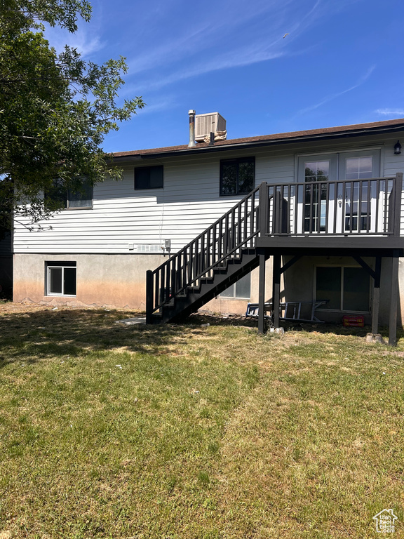 Back of property featuring stairway, a yard, a wooden deck, and cooling unit