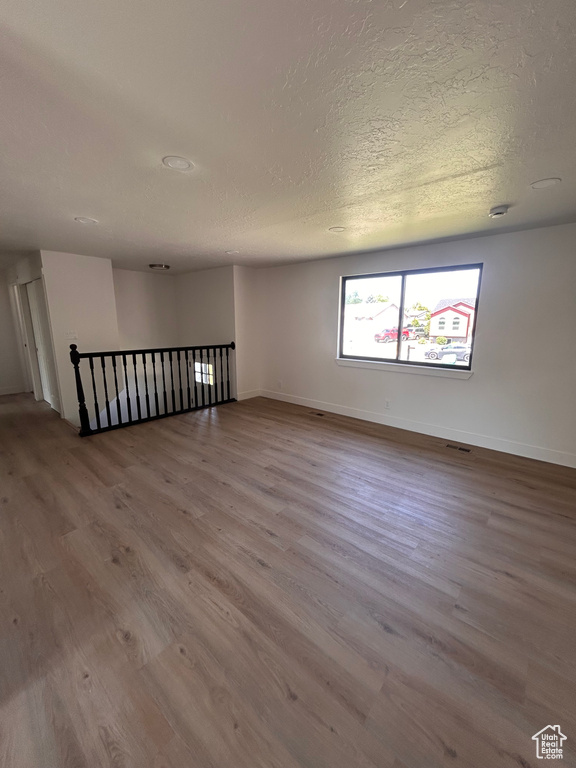 Unfurnished room featuring wood finished floors, baseboards, and a textured ceiling