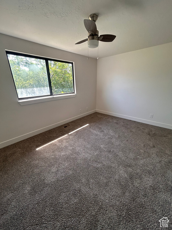 Carpeted spare room featuring baseboards and ceiling fan