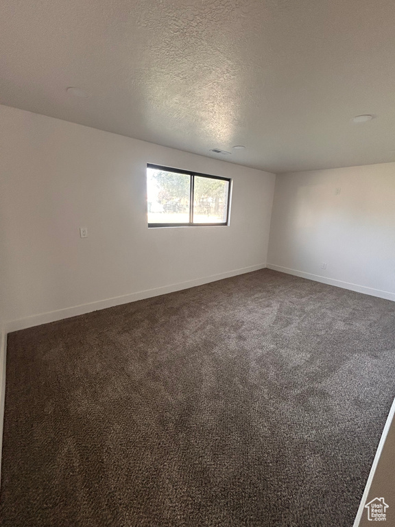 Spare room with baseboards, carpet flooring, and a textured ceiling