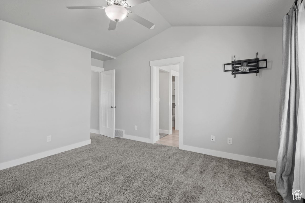 Unfurnished room with ceiling fan, vaulted ceiling, carpet, and baseboards